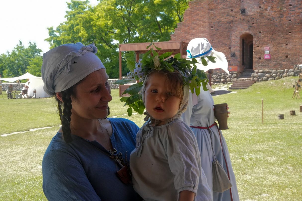 matka w średniowiecznym stroju trzyma na rękach małą dziewczynkę z wiankiem na głowie