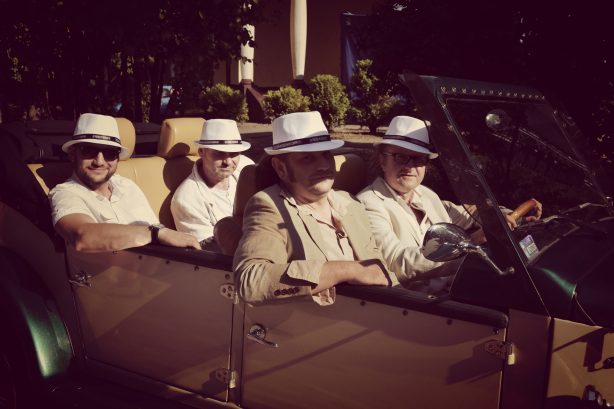grupa czerwie ubrana w modę z XX wieku siedzi w samochodzie